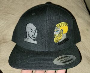A flat-brimmed balck hat featuirng embroidered memes: one the "angry NPC" face, the other the "yes chad" face